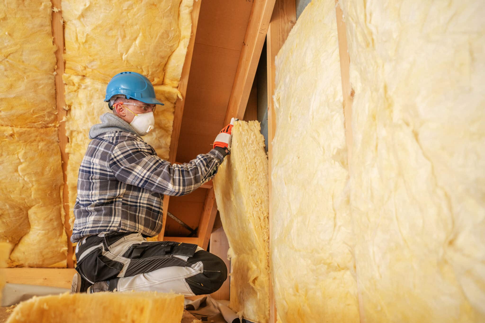 A worker installing attic insulation to increase the lifespan of a roof and the comfort of a home.